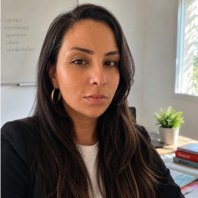 Hadhemi Saidi à son bureau, devant un tableau où sont écrits les mots lernen, verstehen, sprechen, üben, wiederholen